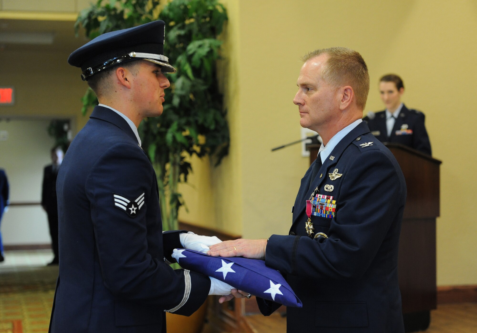 Senior Airman Dylan Anderson, Keesler Honor Guard member, presents the U.S. flag to Col. Dennis Scarborough, 81st Training Wing vice commander, during his retirement ceremony at the Bay Breeze Event Center June 28, 2016, on Keesler Air Force Base, Miss. Scarborough retired with 27 years of military service. He has served multiple tours as an F-15C instructor and evaluator and has held positions in the fields of defense policy, operational plans, safety and aircraft maintenance. He has commanded at the squadron level and served as an operations group deputy commander. (U.S. Air Force photo by Kemberly Groue/Released)