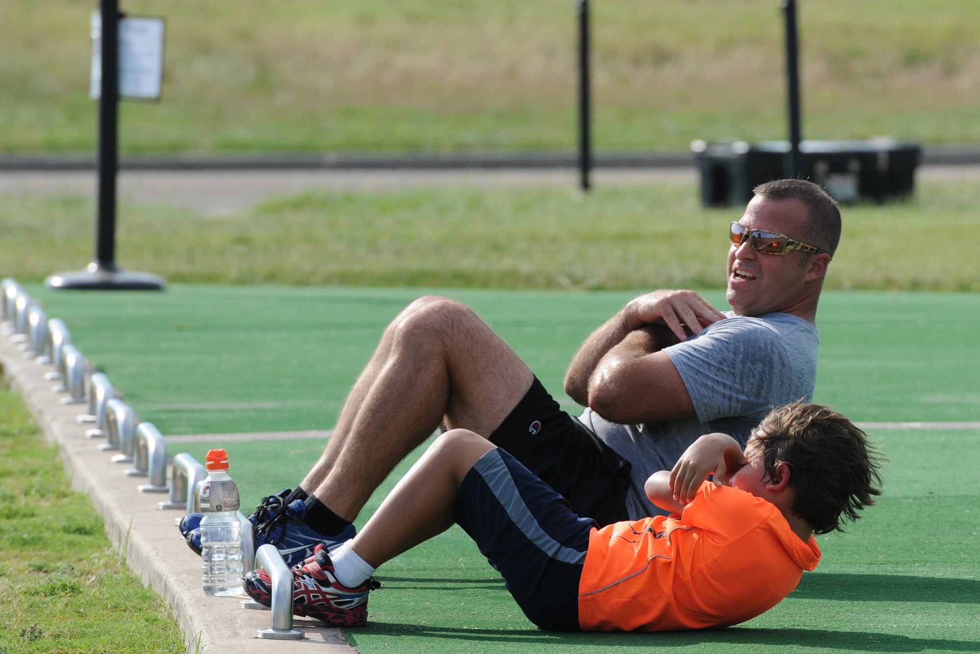 Chief Master Sgt. Derek Fromenthal, 338th Training Squadron superintendent, and his son, D’Anthony, do sit-ups during the Obstacle Warrior Dash 5K at the Triangle track June 27, 2016, on Keesler Air Force Base, Miss. The 81st Force Support Squadron-sponsored event involved participants completing a 5K run then making their way through eight different obstacles. (U.S. Air Force photo by Kemberly Groue/Released)