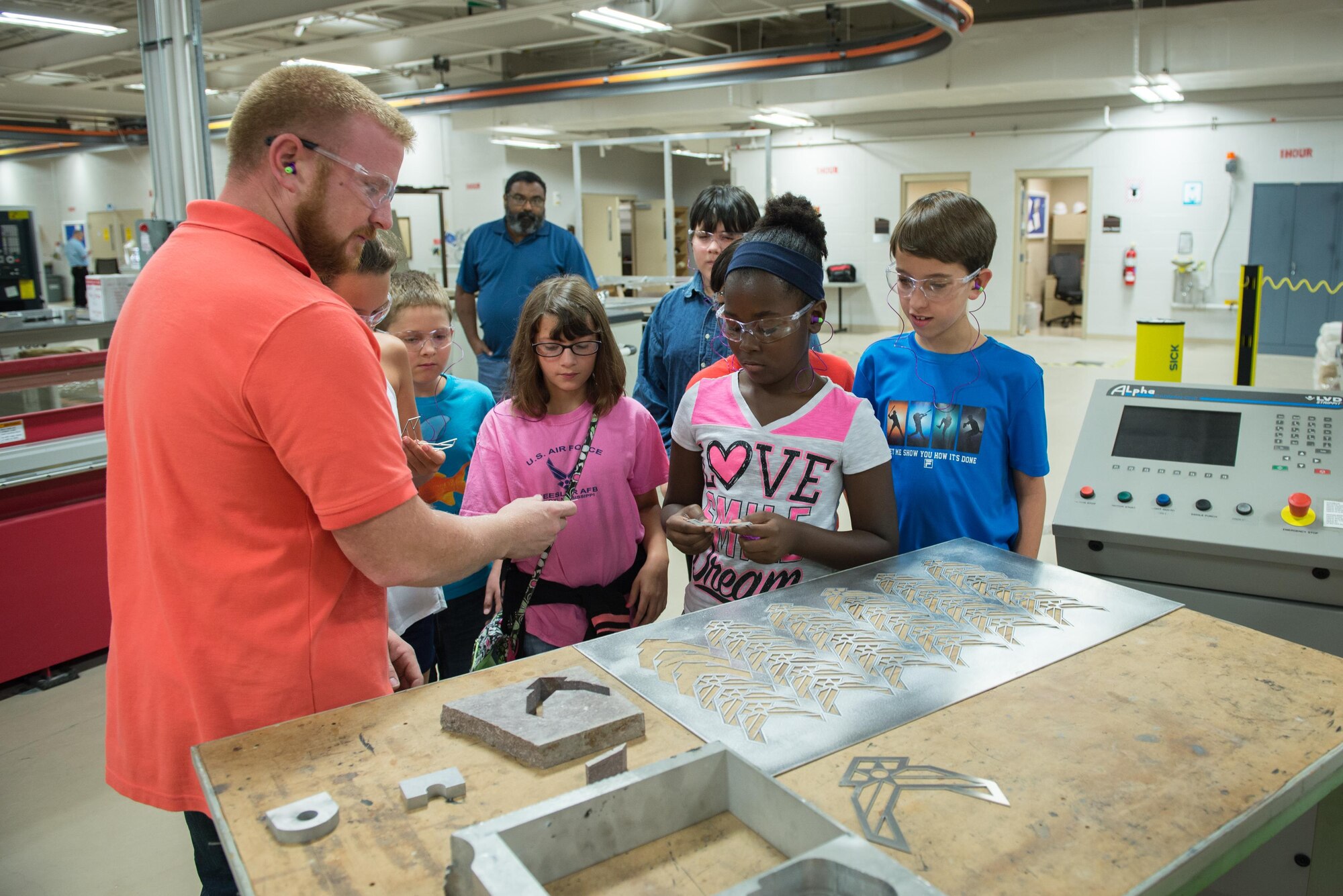 James McCanless, 336th Training Squadron machinist, distributes Air Force logo metal cuts to visiting  Science, Technology, Engineering, and Mathematics Camp students June 23, 2016, on Keesler Air Force Base, Miss. Keesler partnered with the Biloxi School District, Biloxi, Miss. in a week-long summer program designed to educate and enrich middle school students interested in science, technology, engineering or mathematics. (U.S. Air Force photo by Marie Floyd/Released)