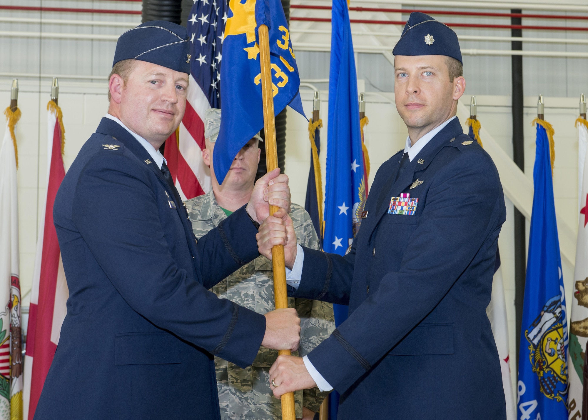 Col. Ryan Suttlemyre, 33rd Operations Group commander, passes the 33rd Operations Support Squadron guidon to Lt. Col. Scott Gunn, 33rd OSS commander, during the 33rd OSS change of command ceremony June 24, 2016, at Eglin Air Force Base, Fla. The 33rd OSS oversees F-35 weapons and tactics training and aircrew flight equipment training at Eglin AFB as well as the training syllabus and operational intelligence training for both AFSOC and the F-35 program at Eglin AFB. (U.S. Air Force photo by Senior Airman Stormy Archer/Released)