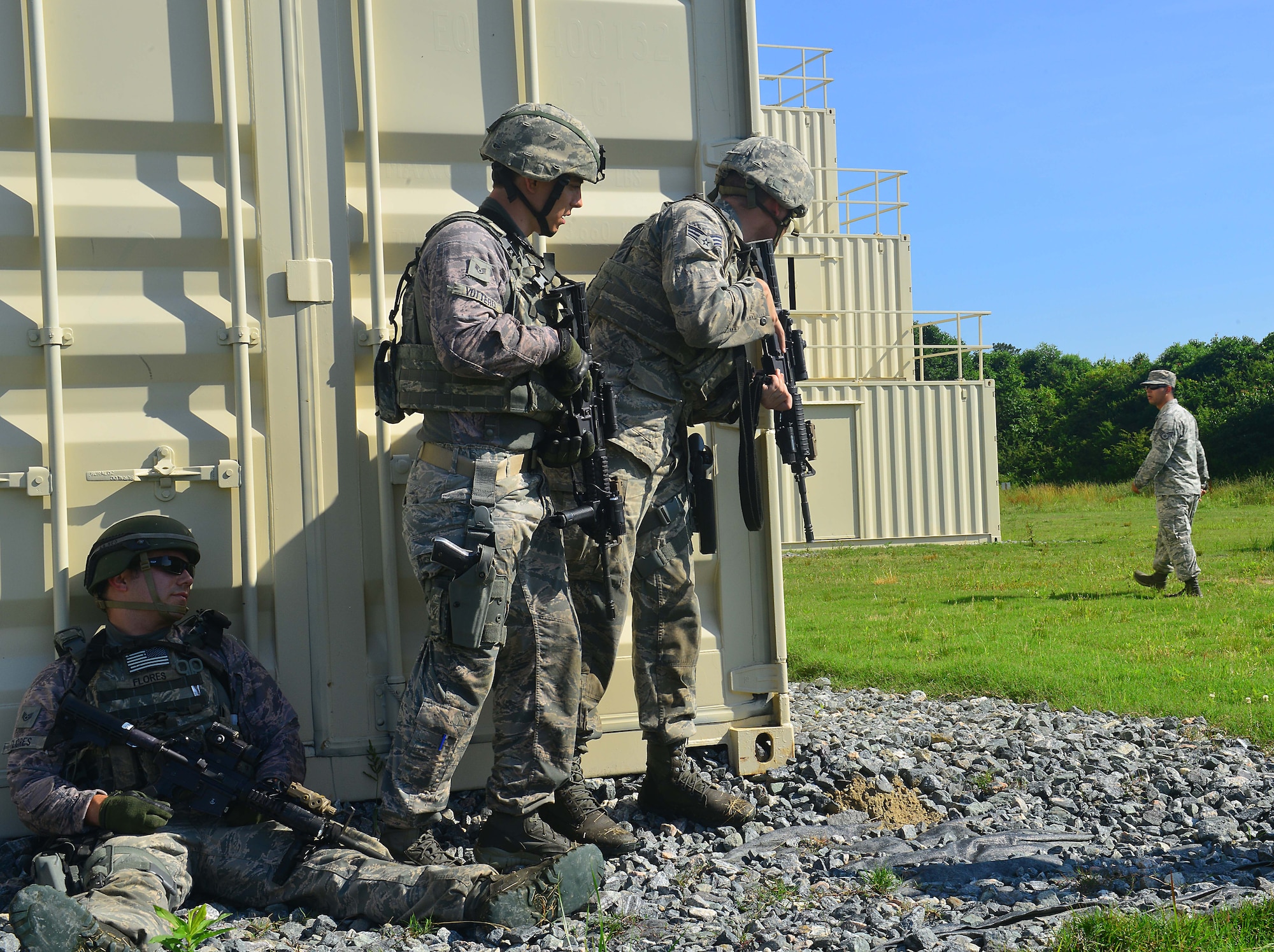 U.S. Air Force Senior Airman Mark Welch, 633rd Security Forces Squadron, installation entry controller provides security while Staff Sgt. Ryan Vottero (center), 633rd SFS, Base Defense Operations Center operator receives situation reports from squad before proceeding to clear mock control tower building during Combat Readiness Training at Langley Air Force Base, Va., June 27, 2016. Base security operations is one of eight blocks of instruction taught at CRT acting as a refresher/prerequisite for predeployment training.  (U.S. Air Force photo by/Tech. Sgt. Daylena S. Ricks)