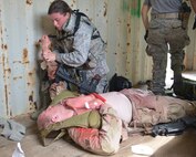 Airman First Class Savannah Spearin, 51st Combat Communications Squadron, attends to a wounded Senior Airman Dakota Schalow, 51st CBCS. Schalow was wounded in a simulated attack on the village he was guarding during recent training exercises. (U.S. Air Force photo by Ray Crayton)