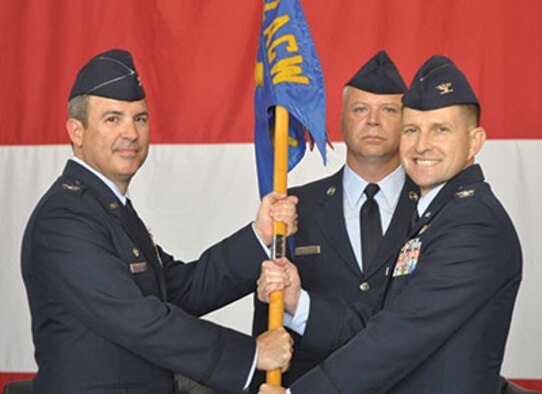 Col. David Gaedecke, 552nd Air Control Wing commander, left, passes the 552nd Air Control Group guidon to Col. Dominic Setka during the change of command ceremony held June 23 in Dock 2, Hangar 230. Colonel Setka assumes command from Col. Michael Homola. Chief Master Sgt. Thomas Cimenski, 552nd Air Control Group superintendent, center, prepares to receive the guidon from Colonel Setka. (Air Force photo by Ron Mullan/Released) 