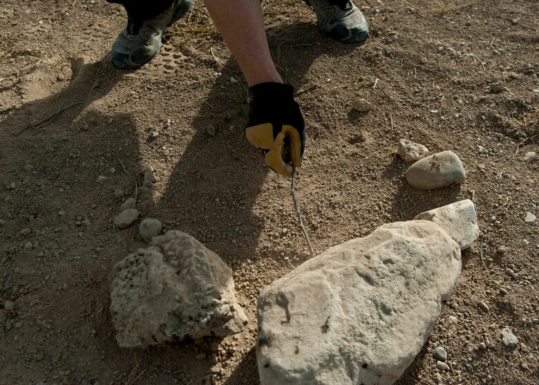 Mr. Ben Allen, U.S. Department of Agriculture Wildlife Services wildlife specialist and biologist, uses a stick to evenly spread out dirt on a manmade wildlife trap he constructed, June 30, 2016, Bagram Airfield, Afghanistan. Wildlife traps like these are used to trap live animals and relocate them off the airfield in order to ensure safer flying operations. (U.S. Air Force photo by Capt. Korey Fratini)