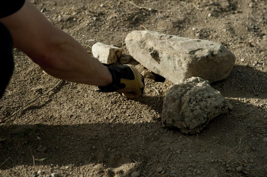 Mr. Ben Allen, U.S. Department of Agriculture Wildlife Services wildlife specialist and biologist, moves rocks around as he constructs a manmade wildlife trap, June 30, 2016, Bagram Airfield, Afghanistan. Wildlife traps like these are one of the ways the USDA and the 455th Air Expeditionary Wing Safety office provide wildlife mitigation services across the airfield ensuring safer flying operations. (U.S. Air Force photo by Capt. Korey Fratini)