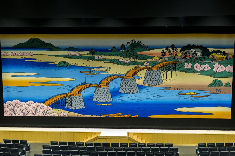 The stage curtain is draped for residents to view in conclusion at the grand opening ceremony of the Command Assembly Hall at Marine Corps Air Station Iwakuni, Japan, July 1, 2016. Operated by Marine Corps Community Services, the building contains a new 29,000 square foot theater with a modern stage, state-of-the art seating, expanded concessions, 3-D projection and a powerful sound system. A stage curtain provided by the Japanese depicts the historic Iwakuni Kintai Bridge using Ukiyo-e style of Japanese woodblock print, which symbolizes the bond and partnership the air station maintains with the local community. (U.S. Marine Corps photo by Lance Cpl. Aaron Henson/Released)