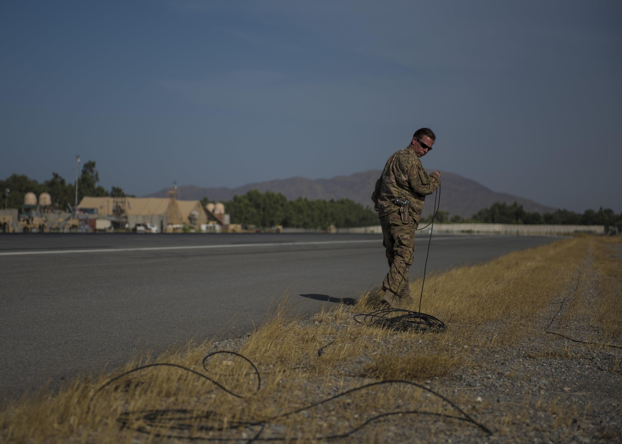 Tech. Sgt. Brent Spotts, 455th Expeditionary Operational Support Squadron dirt boy, pulls on electrical wire for an emergency airfield lighting system (EALS), July 1, 2016, Jalalabad Airfield, Afghanistan. Spotts replaced a 200 foot section of the EALS system after he discovered a faulty portion of wire that wraps around the entire airfield. (U.S. Air Force photo by Senior Airman Justyn M. Freeman)