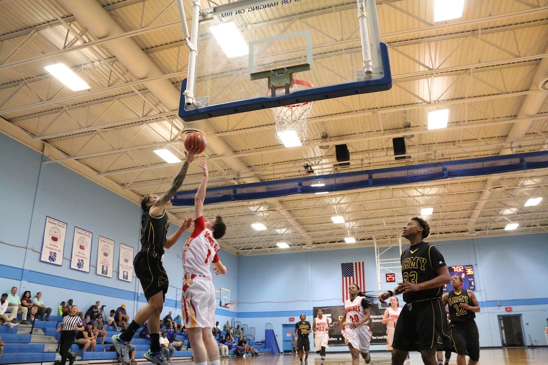 Army Spc. Vanessa Laminson (left) of Fort Bliss, Texas hits the lay-up over Marine Corps Lance Cpl. Alyshia Crawford (#1) of Quantico, Va. during Army's win over Marine Corps 103-19 in Game Four of the 2016 Armed Forces Women's Basketball Championship in the Chaparrel Fitness Center at Joint Base San Antonio-Lackland AFB, Texas on 2 July.  