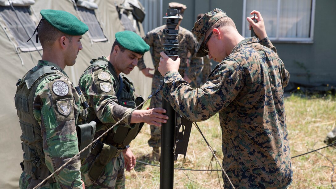 U.S. Marine Corps Lance Cpl. Colby Goranson, a radio operator with Special Purpose Marine Air-Ground Task Force-Crisis Response-Africa, works with Portuguese soldiers to set up communications equipment during Exercise Orion 16 at military training area Tancos, Portugal, June 22, 2016. Goranson was in charge of communication between the Marine quick response force and the forward operating base during the exercise. 