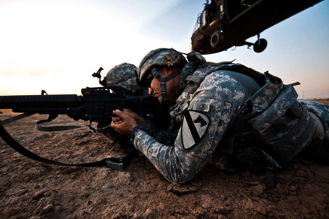 After air assaulting into a landing zone, Spc. Khalid Hermez, from Detroit, pulls security as a UH-60 Black Hawk helicopter departs the landing zone. U.S. Soldiers from the 1st Air Cavalry Brigade and the 34th Iraqi Army Brigade performed a joint air assault mission and patrol to check on living conditions of a small village north of here, Nov. 12. (Photo by Sgt. Travis Zielinski)