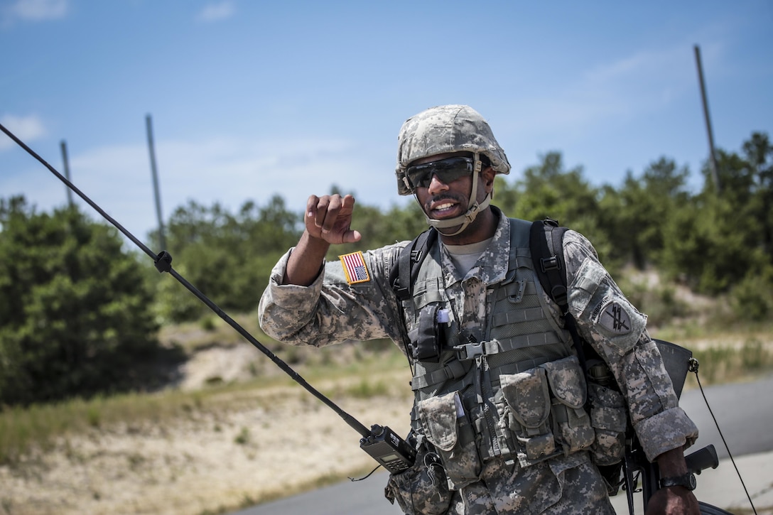 A U.S. Army Reserve Soldier from the 404th Civil Affairs Battalion signals to his patrol to check an approaching pedestrian during Exercise Gridiron at Joint Base McGuire-Dix-Lakehurst, N.J., June 27, 2016. (U.S. Air National Guard photo by Tech. Sgt. Matt Hecht/Released)