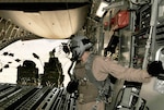 Senior Airman Rory Nowosielski stands on the ramp as container delivery system bundles exit the aircraft during a high-altitude airdrop mission in a C-17 Globemaster III Feb. 14 over Afghanistan. Airman Nowosielski is a C-17 loadmaster with the 816th Expeditionary Airlift Squadron.