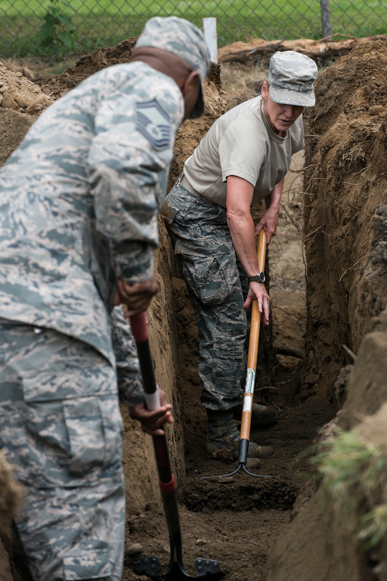 U.S. Air Force Airmen from the 307th Civil Engineering Squadron (CES) level dirt in a trench prior to laying new plumbing and electrical lines at the Chenango County Fairgrounds, Norwich, N.Y., June 28, 2016. The 307th CES is an Air Force Reserve squadron assigned under the 307th Bomb Wing at Barksdale Air Force Base, La., and is in Norwich to participate in a community restoration project in support of the Innovative Readiness Training Program.  (U.S. Air Force photo by Master Sgt. Greg Steele/Released)