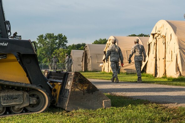 U.S. Air Force Airmen from the 307th Civil Engineering Squadron (CES) walk along tent row at the camp they have set up on the Chenango County Fairgrounds, Norwich, N.Y., July 1, 2016. The 307th CES is an Air Force Reserve squadron assigned under the 307th Bomb Wing at Barksdale Air Force Base, La., and lived under deployment conditions while participating in a renovation project as part of the Innovative Readiness Training Program.  (U.S. Air Force photo by Master Sgt. Greg Steele/Released)