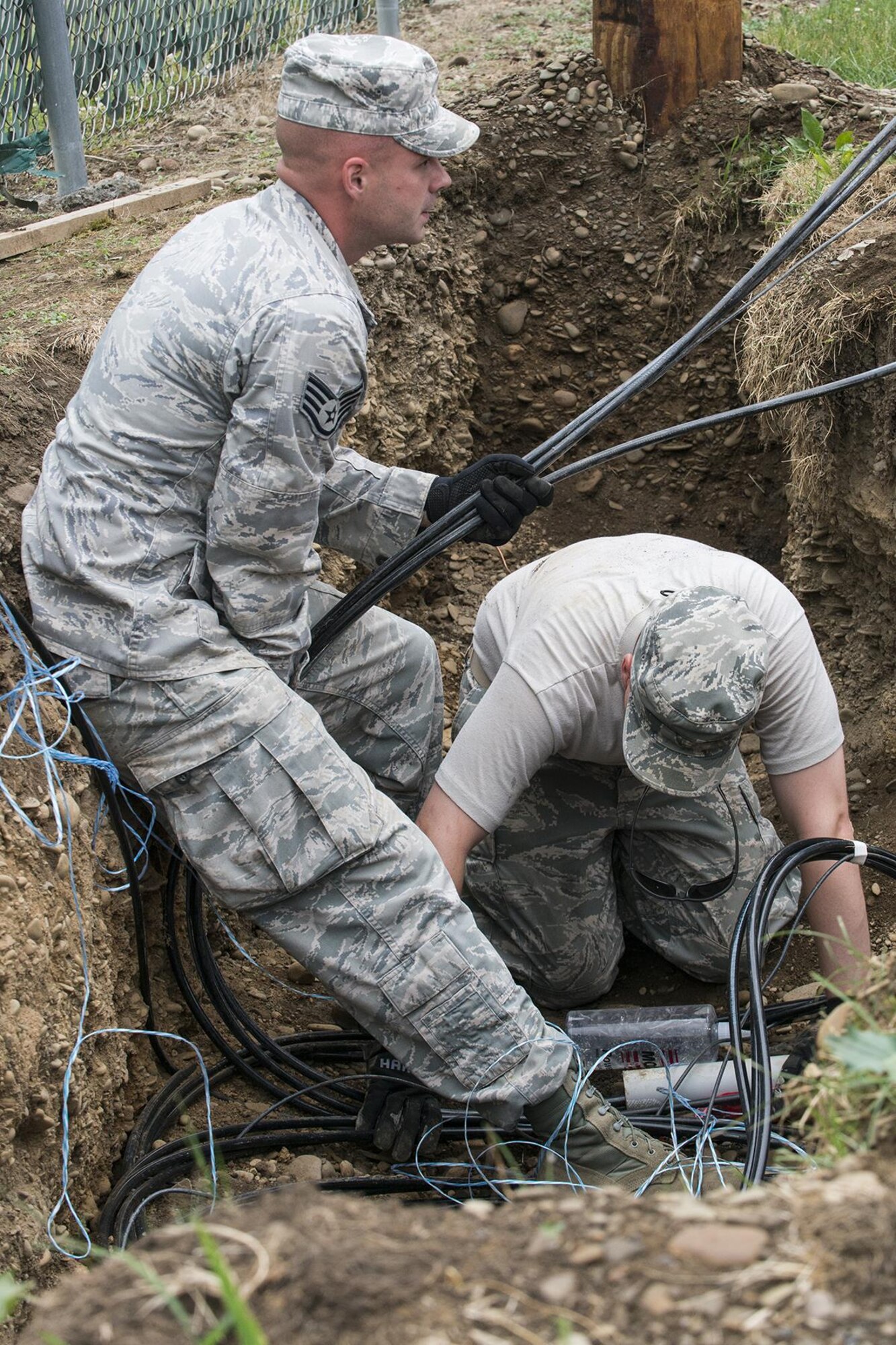 U.S. Air Force Airmen from the 307th Civil Engineering Squadron (CES) feed electrical lines through conduit laid underground at the Chenango County Fairgrounds, Norwich, N.Y., June 28, 2016. The 307th CES is an Air Force Reserve squadron assigned under the 307th Bomb Wing at Barksdale Air Force Base, La., and is in Norwich to participate in a community restoration project in support of the Innovative Readiness Training Program.  (U.S. Air Force photo by Master Sgt. Greg Steele/Released)