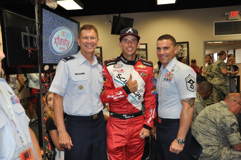 Brig. Gen. Wayne Monteith, 45th Space Wing commander, left, and Chief Master Sgt. Jason Lamoureux, 45th SW command chief, pose for a photo with NASCAR driver Ray Black Jr. at the NASCAR Drivers and Crew Chiefs meeting at Daytona International Speedway July 1, 2016. NASCAR driver Ray Black Jr. from SS Green Light Racing supported the wing by displaying the 45th Space Wing name across the windshield of his Chevrolet Camaro No. 07 racecar during the race instead of the typical Xfinity logo that is displayed for Xfinity races. (U.S. Air Force photo by 1st Lt. Alicia Premo/Released)