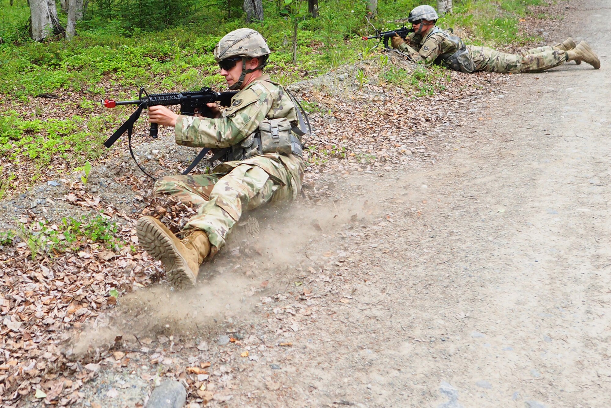 Army Sgt. Patric Carroll, a native of Englewood, Tenn., assigned to the 539th Composite Truck Company (Light), 17th Combat Sustainment Support Battalion, U.S. Army Alaska, slides on his side into a shallow ditch as a fellow soldier provides covering fire for him on a Situation Exercise Training lane during the Ready Warrior Competition at Camp Madbull on Joint Base Elmendorf-Richardson, Alaska, Thursday, June 23, 2016.  The three-day competition tested teams of Soldiers in physical fitness, small arms proficiency, land navigation, and small-unit tactics as well as other Soldier skills. (U.S. Air Force photo/Justin Connaher)