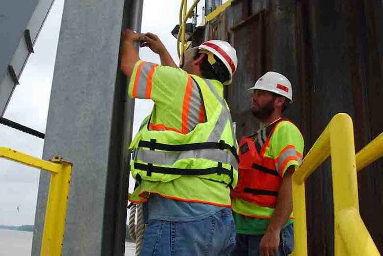 Left to right,George Baddour and Hafford Barton put pipes in place that will run a cable from the underwater portion of the gage to the Data Collection Platform (DCP) box.