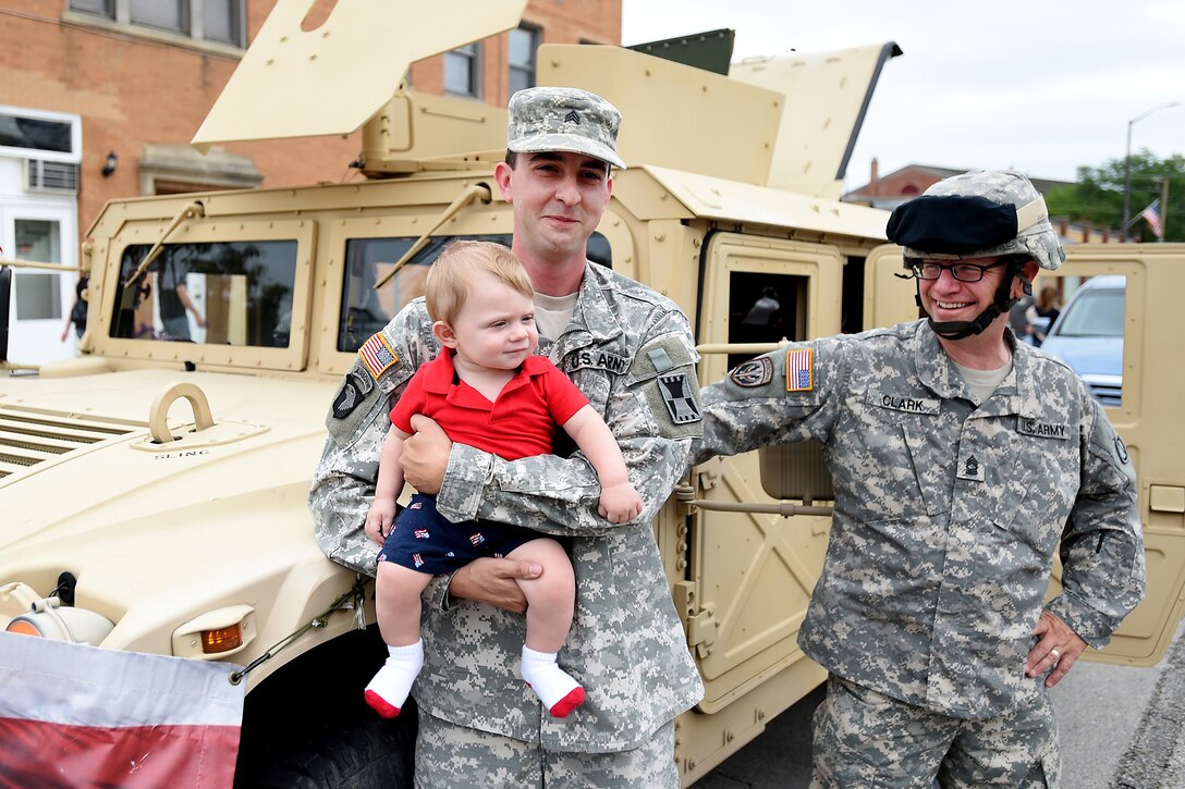 Sgt. Adam Burson, holding seven-month-old Dylan Blicharz of Melrose Park, with Master Sgt. Keith Clark, 85th Support Command stand in front of a Humvee before the Villa Park annual Fourth of July parade, July 4, 2016.
(U.S. Army photo by Spc. David Lietz/Released)