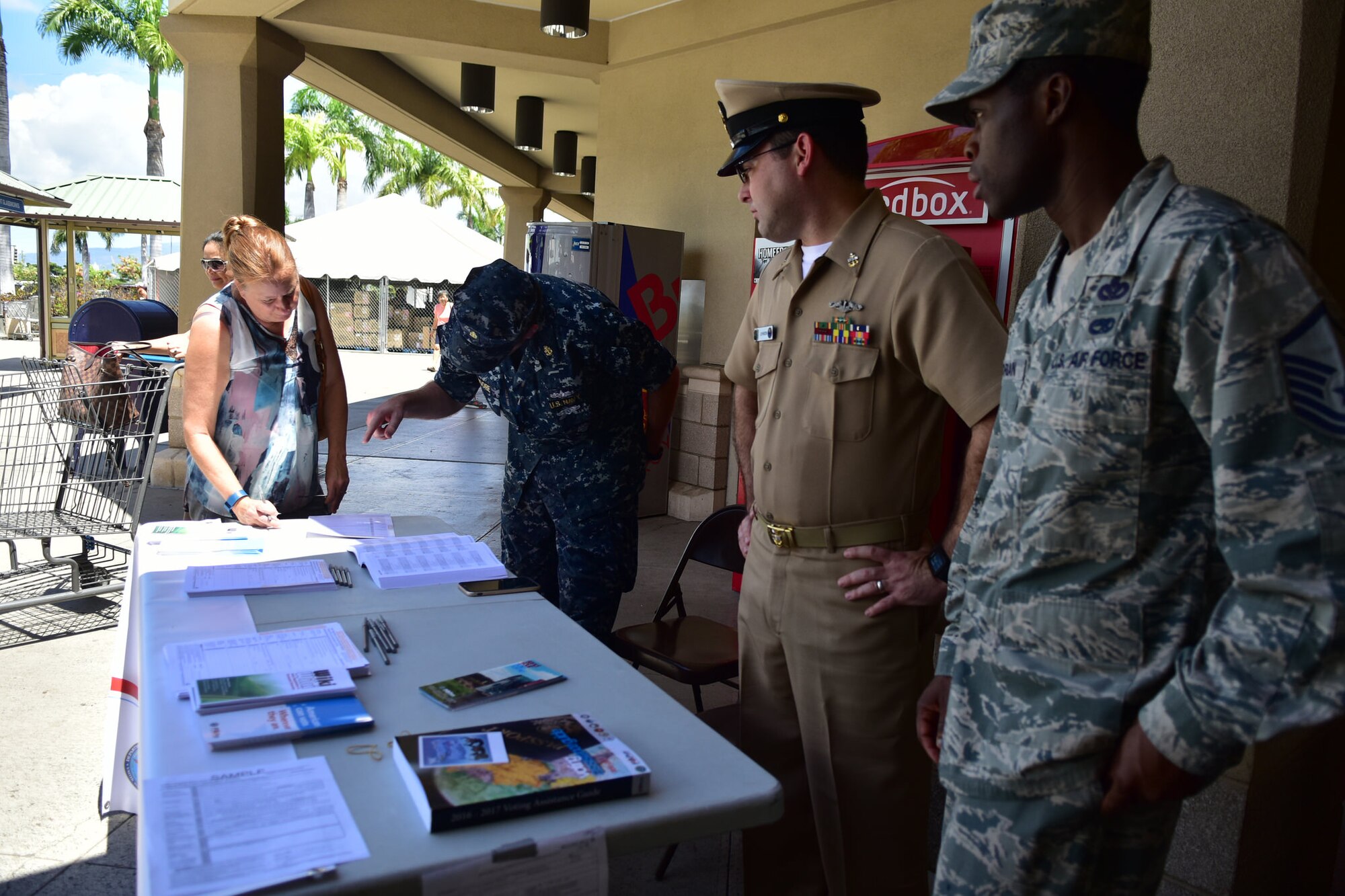 Navy Senior Chief Leon Johnson, Chief Patrick Moore and Master Sgt. Alfred Morgan assist a potential voter during the JBPHH Voting Outreach Committee's assistance event, held June 29. The event, which was held on Hickam and the Navy Exchange, afforded service members and civilians alike the opportunity to register to vote. (U.S. Air Force photo by Staff Sgt. Christopher Stoltz)
