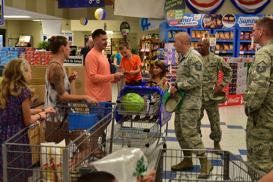 Members of Operation Warmheart give commissary patrons gift cards during a surprise event, held Thursday, June 30 at the Hickam Commissary. During this trip, Operation Warmheart handed out 40 commissary gift cards totaling $1,500 to military members and their families. Operation Warmheart is an Air Force non-profit organization that distributes charitable funds to JBPHH service members and their families. (Air Force photo by Staff Sgt. Christopher Stoltz)
