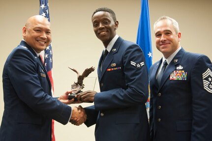 Airman 1st Class Isiah Briggs, 437th Maintenance Squadron crew chief, receives the Distinguished Graduate Award from Colonel Jimmy Canlas, 437th Airlift Wing commander and Chief Master Sgt. Kristopher Berg, 437th Airlift Wing command chief during the honor guard graduation ceremony held in the Education and Training Center June 30, 2016, Joint Base Charleston, S. C. Honor guard members are chosen for their steadfast dedication to the integrity, service and excellence required to bring honor to the ceremonies the Air Force holds dear. (U.S. Air Force Photo/Senior Airman Kristin Kurtz)