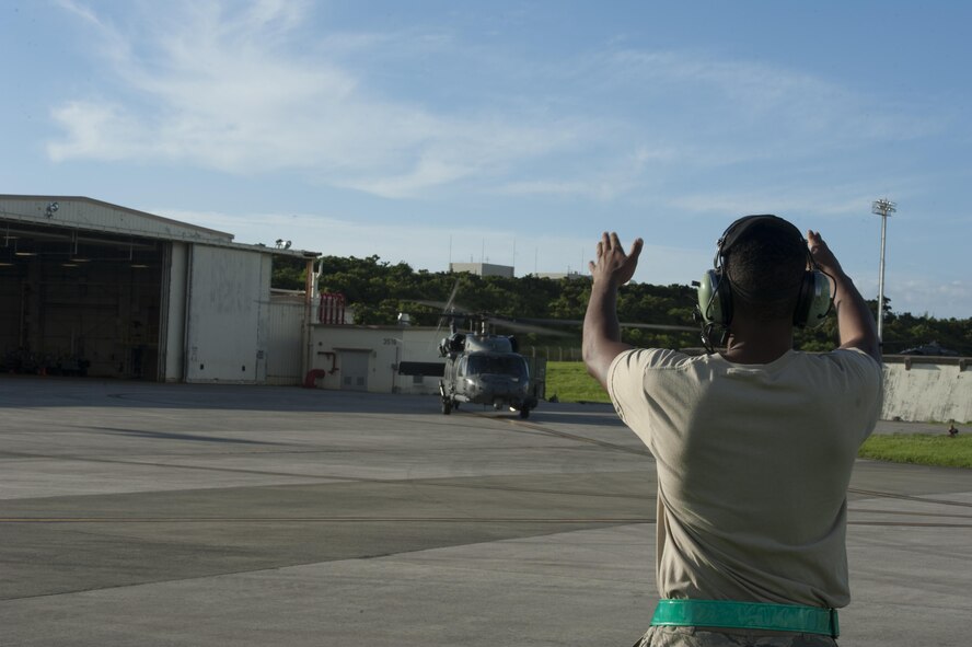 U.S. Air Force Airman 1st Class Sean Woolridge, 33rd Helicopter Maintenance Unit, guides an HH-60G Pave Hawk as it prepares to take off June 20, 2016, at Kadena Air Base, Japan. The 33rd HMU underwent training for Exercise Pacific Thunder. (U.S. Air Force photo by Airman 1st Class Lynette M. Rolen)