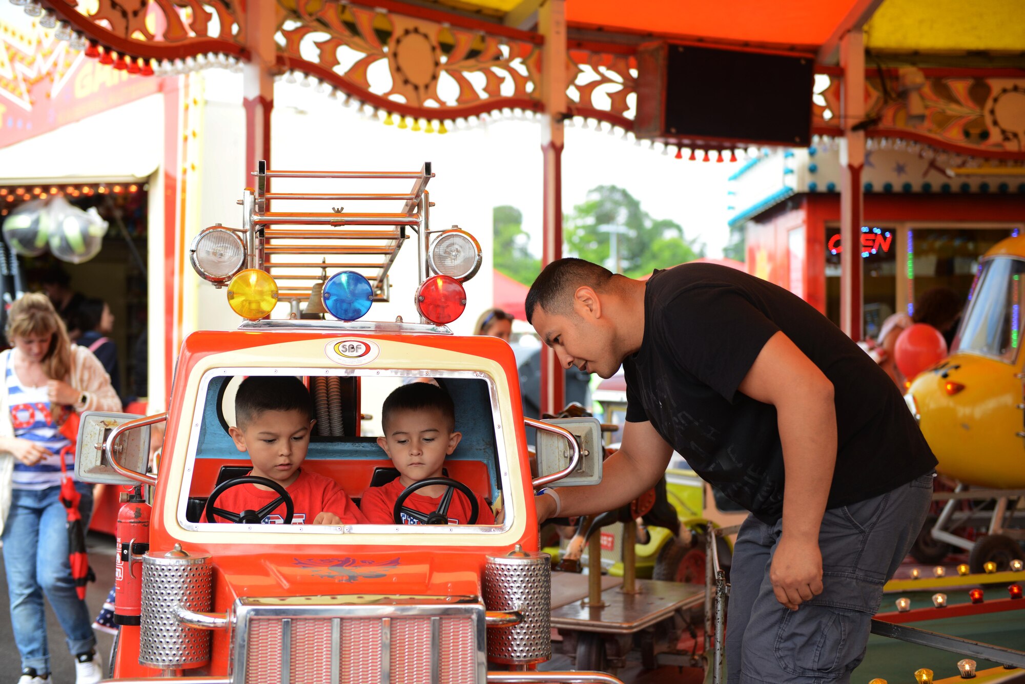 A man sets up his children in a carousel ride during the Freedom Fest 2016 at Ramstein Air Base, Germany, July 4, 2016. The Independence Day celebration included a variety of foods, games, rides and fireworks for Kaiserslautern Military Community members. (U.S. Air Force Photo/ Airman 1st Class Joshua Magbanua)