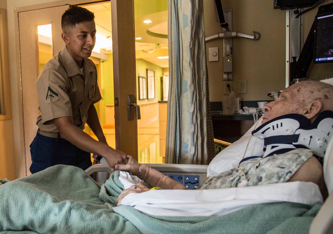 Lance Cpl. Luis Acosta, a maintenance management specialist with Combat Logistics Battalion 453, shakes hands with Richard Mathis, a Marine veteran, at the St. Anthony Hospital & Medical Campus in Lakewood, CO June 29, 2016. Mathis suffered a broken neck from a fall that occurred approximately three weeks prior to the visit.