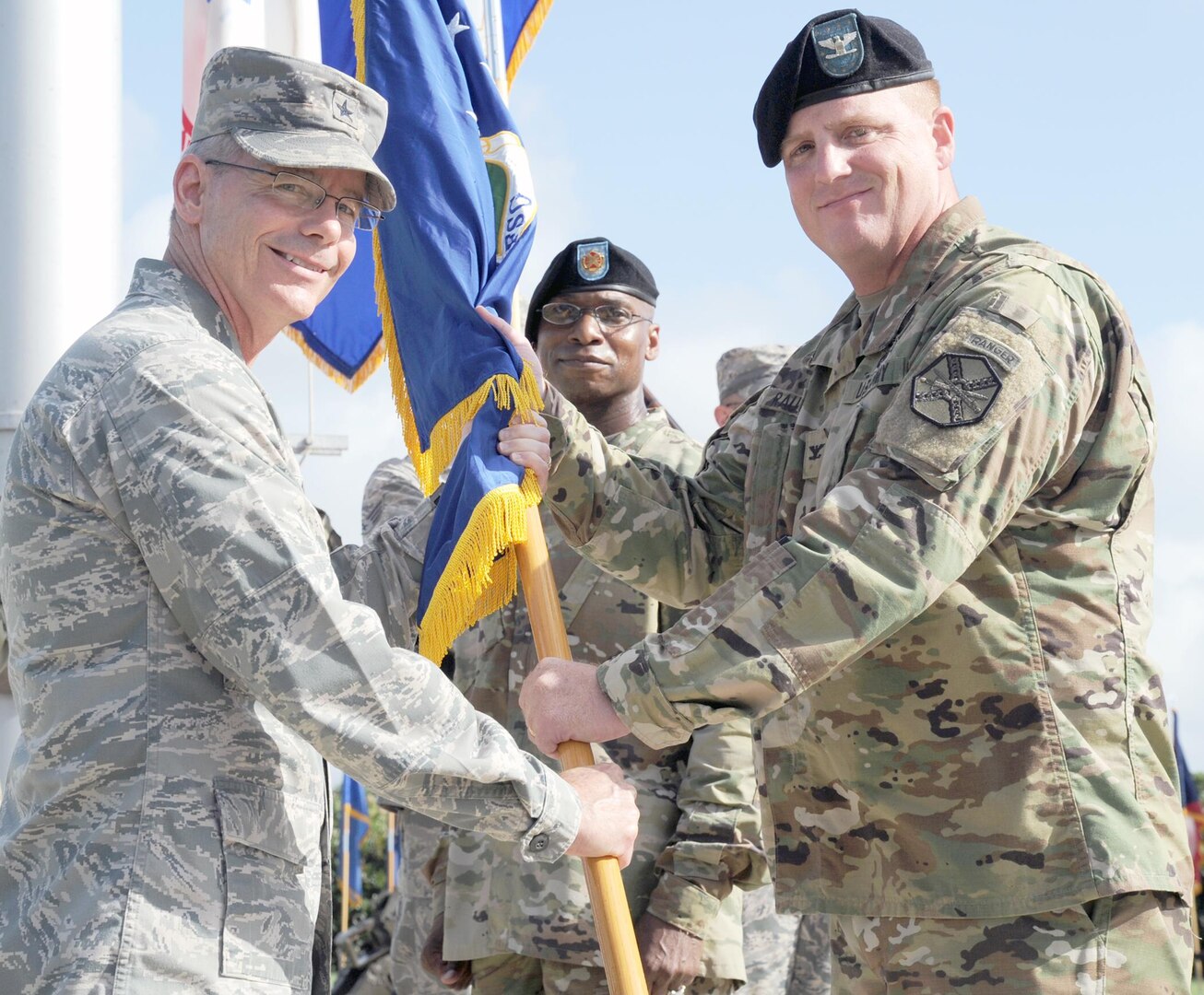 Brig. Gen. Bob LaBrutta (left), 502nd Air Force Base Wing and Joint Base San Antonio commander, passes the 502nd Support Group guidon to Col. David L. Raugh (right), who took over command from Col. Steven A. Toft in a change of command ceremony at Joint Base San Antonio-Fort Sam Houston June 22.