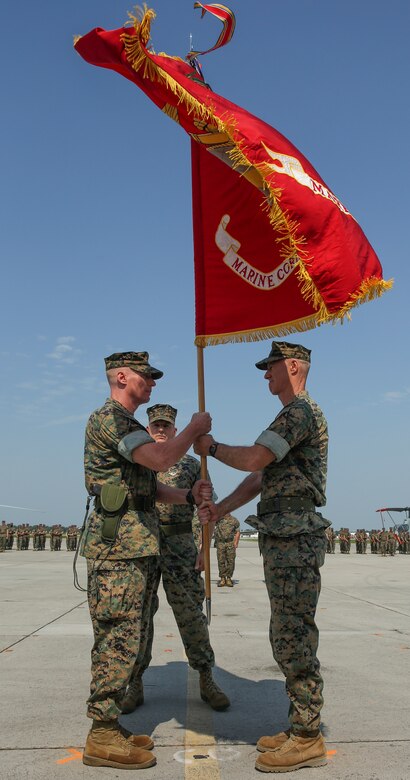 Col. Timothy M. Salmon, outgoing commanding officer, Marine Corps Air Station New River, passes the air station’s colors to Col. Russell C. Burton, symbolizing the transition of leadership during a change of command ceremony at MCAS New River June 23. Col. Salmon relinquished his command of the air station after three years of service as the air station’s commander. 