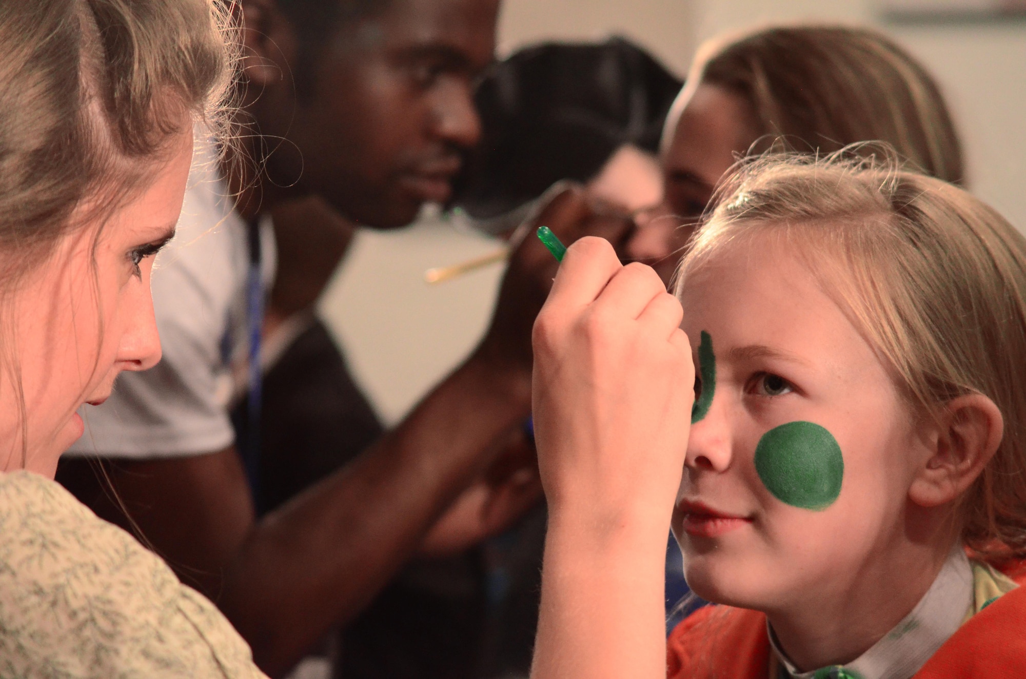 Kate Kesslar, Missoula Children’s Theatre tour actor and director, applies stage makeup to Olivia Armstrong, who played the role of Jiminy Cricket during the MCT presentation of Pinocchio at the base theater on Peterson Air Force Base, July 1, 2016.  For over 40 years MCT has been sending out two person teams to tour across the world and bring the arts to children everywhere.  (U.S. Air Force photo by Staff Sgt. Amber Grimm)