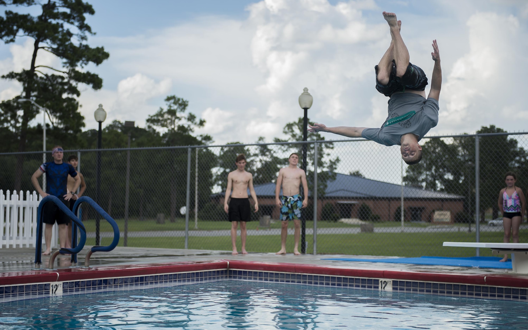 U.S. Air Force Maj. Brandon Wengert, 23d Force Support Squadron commander, flips from a diving board during a contest at the Red, White and Blue Splash Party at the base pool, July 4, 2016 at Moody Air Force Base, Ga. The crowd chose Wengert as the winner of the contest by cheering and shouting for who they thought performed the best. (U.S. Air Force photo by Tech. Sgt. Zachary Wolf/Released)