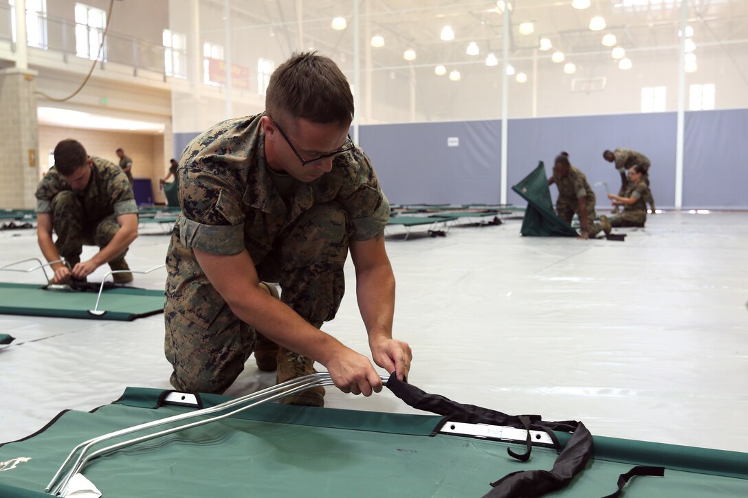 Cpl. Simon Mangold, ground electronic maintenance repair technician with Headquarters and Support Battatalion, breaks down a cot at the primary base shelter at Wallace Creek Fitness Center during a destructive weather exercise on Marine Corps Base Camp Lejeune June 22. The annual exercise helps installation assets practice procedures taken in the event of actual destructive weather. (U.S. Marine Corps photo by Cpl. Mark Watola /Released)