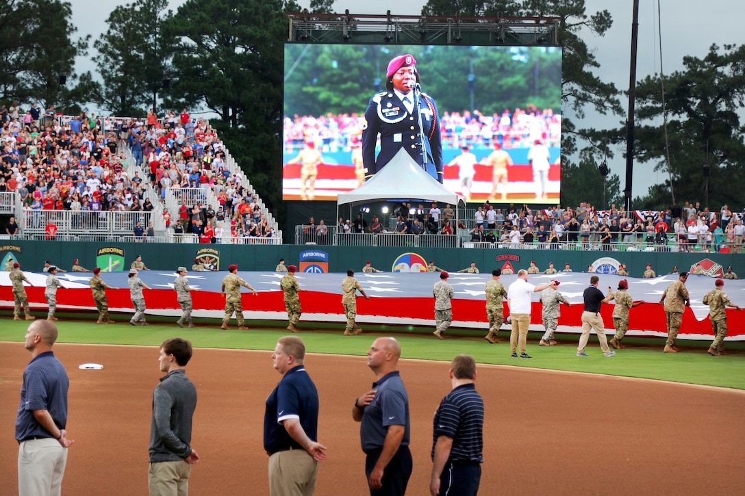 Soldiers display the U.S. flag as Army Staff Sgt. Traci Gregg sings the national anthem before the start of the baseball game between the Florida Marlins and Atlanta Braves at Fort Bragg, N.C., July 3, 2016. Army photo by Staff Sgt. Jason Duhr