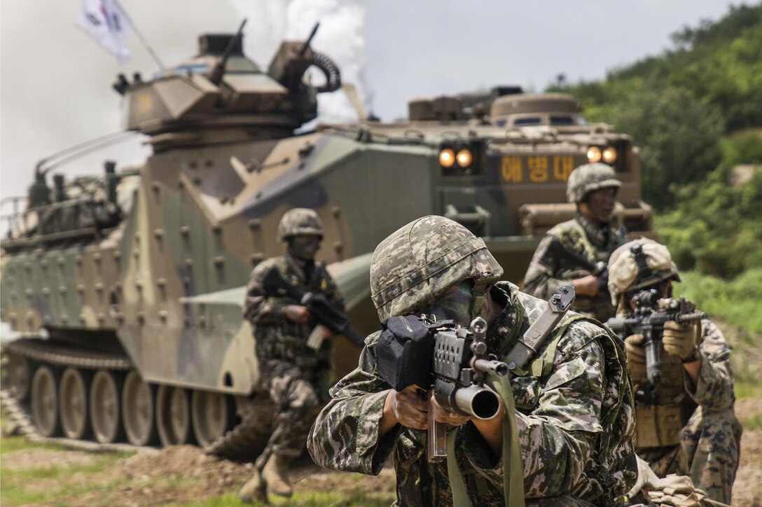 U.S. Marines watch as a South Korean marine aims his rifle and South Korean assault vehicles shoot off smoke at Suseong range in South Korea, July 6, 2016, during a Korean Marine Exchange Program. The program's goal is to enhance the South Korean-U.S. team at the tactical level to build combined war fighting capabilities. Marine Corps photo by Lance Cpl. Amaia Unanue