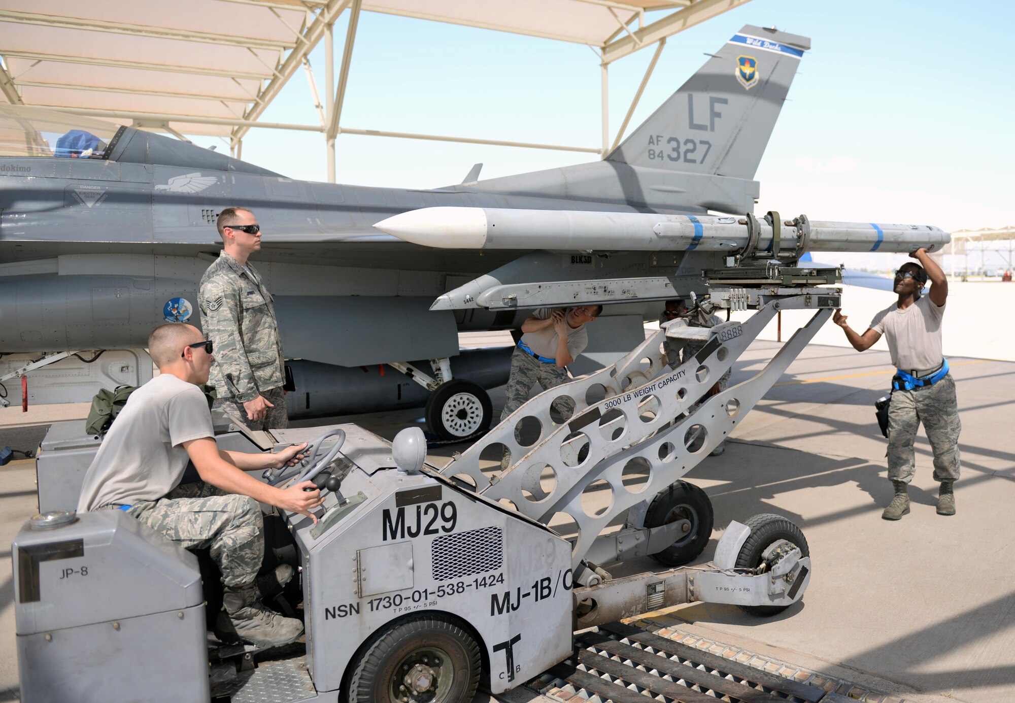 A weapons load crew from the 309th Aircraft Maintenance Unit loads an inert AIM-120 air-to-air missile onto an F-16 during the annual Second Quarter Load Crew Competition July 1, 2016, at Luke Air Force Base. The competition pitted teams from different AMUs against each other in a race to complete the loading of weapons onto either an F-16 or an F-35 first. (U.S. Air Force photo by Airman 1st Class Ridge Shan)