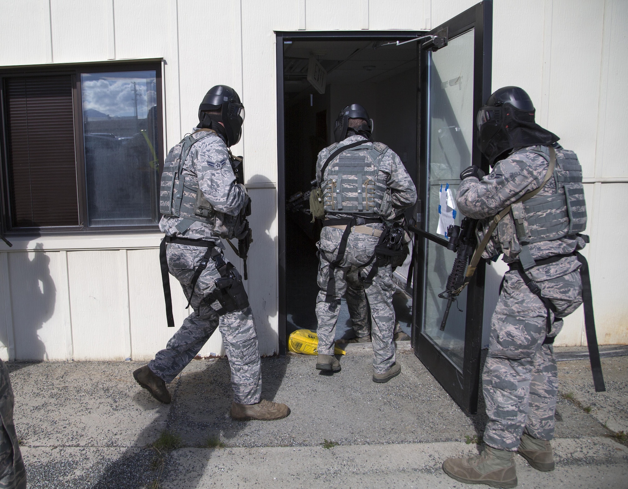 Security forces personnel, assigned to the 673d Security Forces Squadron, enter a building while conducting high risk response training at Joint Base Elmendorf-Richardson, Alaska, June 29, 2016. High risk response training provides security forces personnel an intensive, hands-on course based in various real-life scenarios emphasizing effective tactics to engage and eliminate active shooters or other threats. (U.S. Air Force photo/Alejandro Pena)