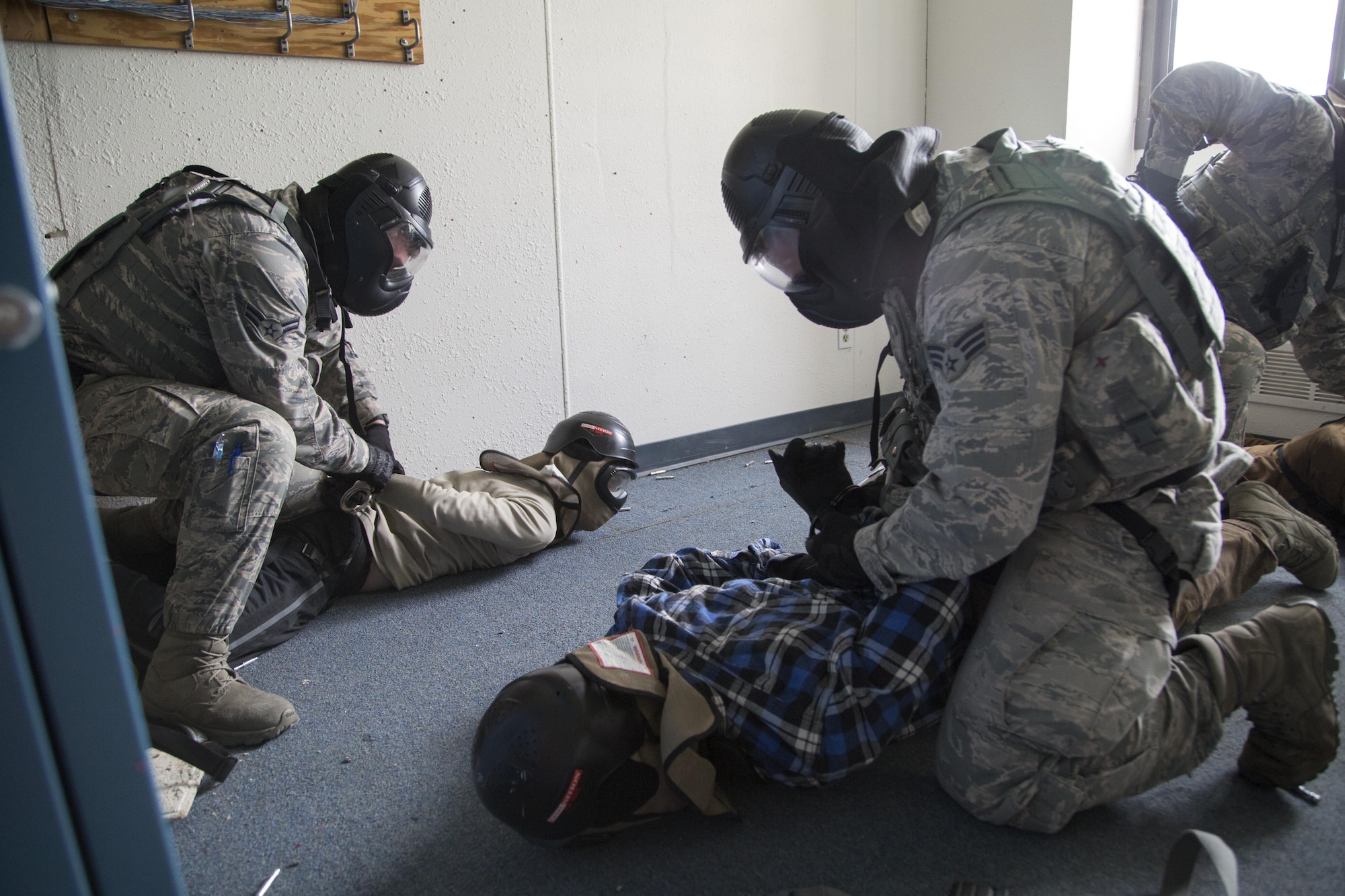Security forces personnel, assigned to the 673d Security Forces Squadron, detain simulated active shooters while conducting high risk response training at Joint Base Elmendorf-Richardson, Alaska, June 29, 2016. High risk response training provides security forces personnel an intensive, hands-on course based in various real-life scenarios emphasizing effective tactics to engage and eliminate active shooters or other threats. (U.S. Air Force photo/Alejandro Pena)