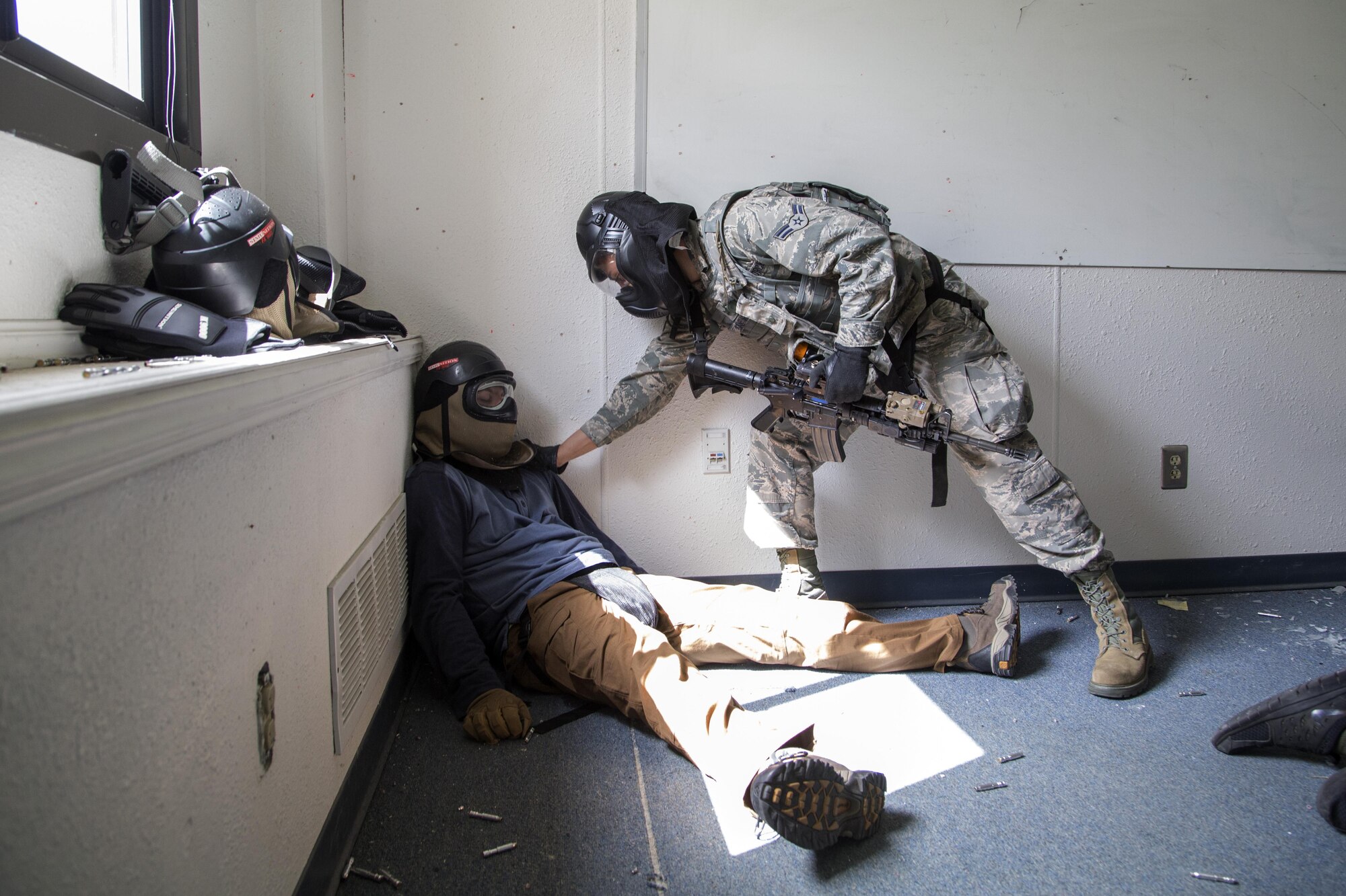 A security forces Airman, assigned to the 673d Security Forces Squadron, assesses a simulated victim while conducting high risk response training at Joint Base Elmendorf-Richardson, Alaska, June 29, 2016. High risk response training provides security forces personnel an intensive, hands-on course based in various real-life scenarios emphasizing effective tactics to engage and eliminate active shooters or other threats. (U.S. Air Force photo/Alejandro Pena)