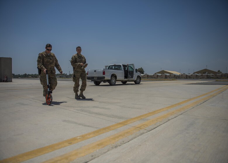 Capt. Laura Ryan (left), 455th Expeditionary Operational Support Squadron, Detachment 1, takes measurements for apron setbacks with the help of Tech. Sgt. Amy Saunders (right), 455th EOSS, Det. 1 airfield management liaison officer, July 1, 2016, Jalalabad Airfield, Afghanistan. Ryan and Saunders are taking measurements for helicopter apron setbacks because they are needed for the new parking plans. (U.S. Air Force photo by Senior Airman Justyn M. Freeman)