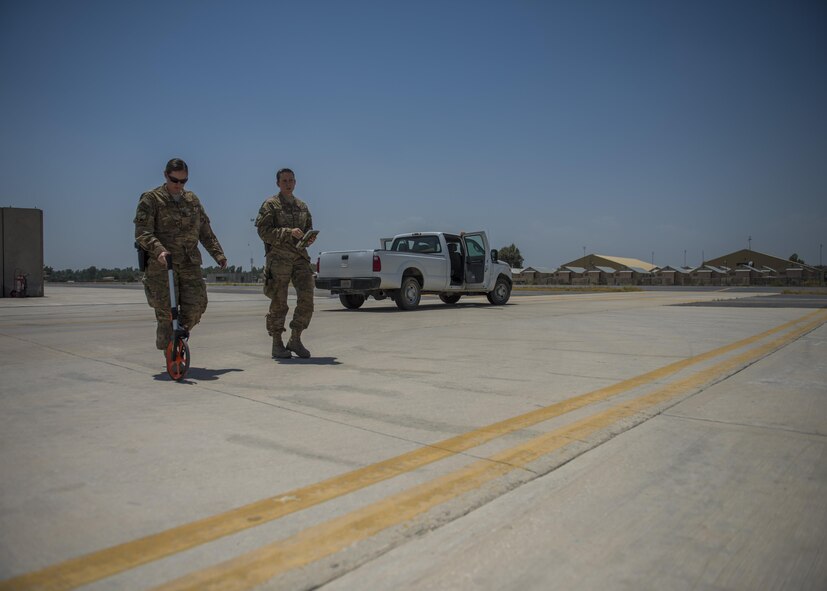 Capt. Laura Ryan (left), 455th Expeditionary Operational Support Squadron, Detachment 1, takes measurements for apron setbacks with the help of Tech. Sgt. Amy Saunders (right), 455th EOSS, Det. 1 airfield management liaison officer, July 1, 2016, Jalalabad Airfield, Afghanistan. Ryan and Saunders are taking measurements for helicopter apron setbacks because they are needed for the new parking plans. (U.S. Air Force photo by Senior Airman Justyn M. Freeman)