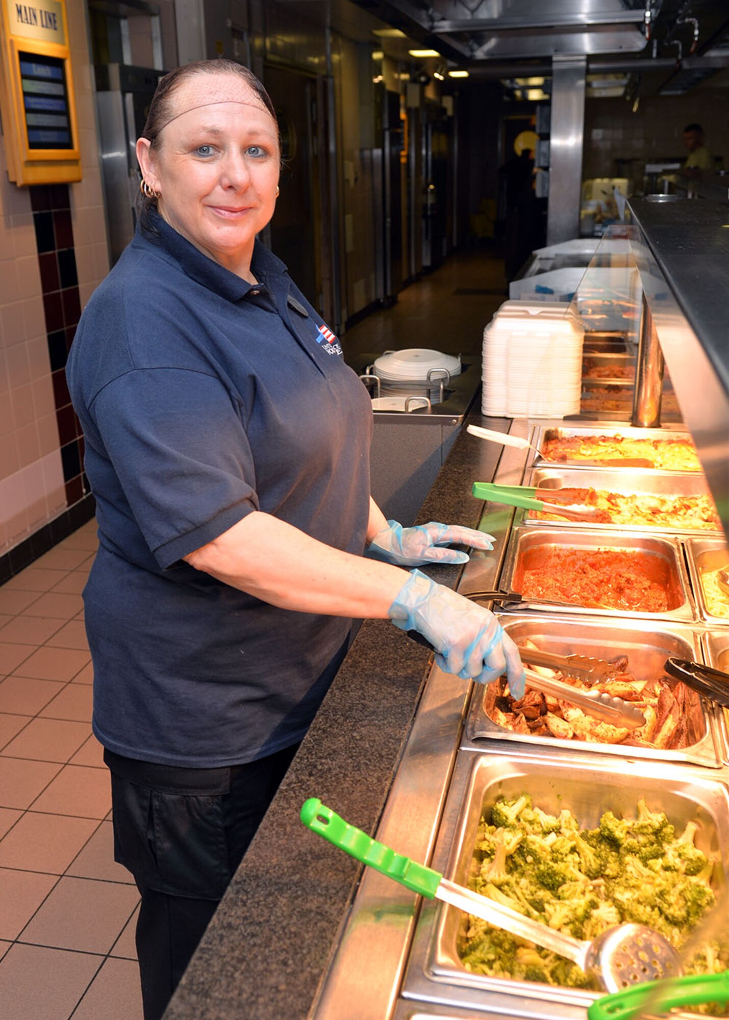 Linda Brady, 100th Force Support Squadron food service worker, prepares to serve food to customers at the Gateway Dining Facility June 29, 2016, on RAF Mildenhall, England. Brady was selected for the Square D Spotlight for exhibiting the Air Force Core Value, Service Before Self. (U.S. Air Force photo by Karen Abeyasekere/Released)