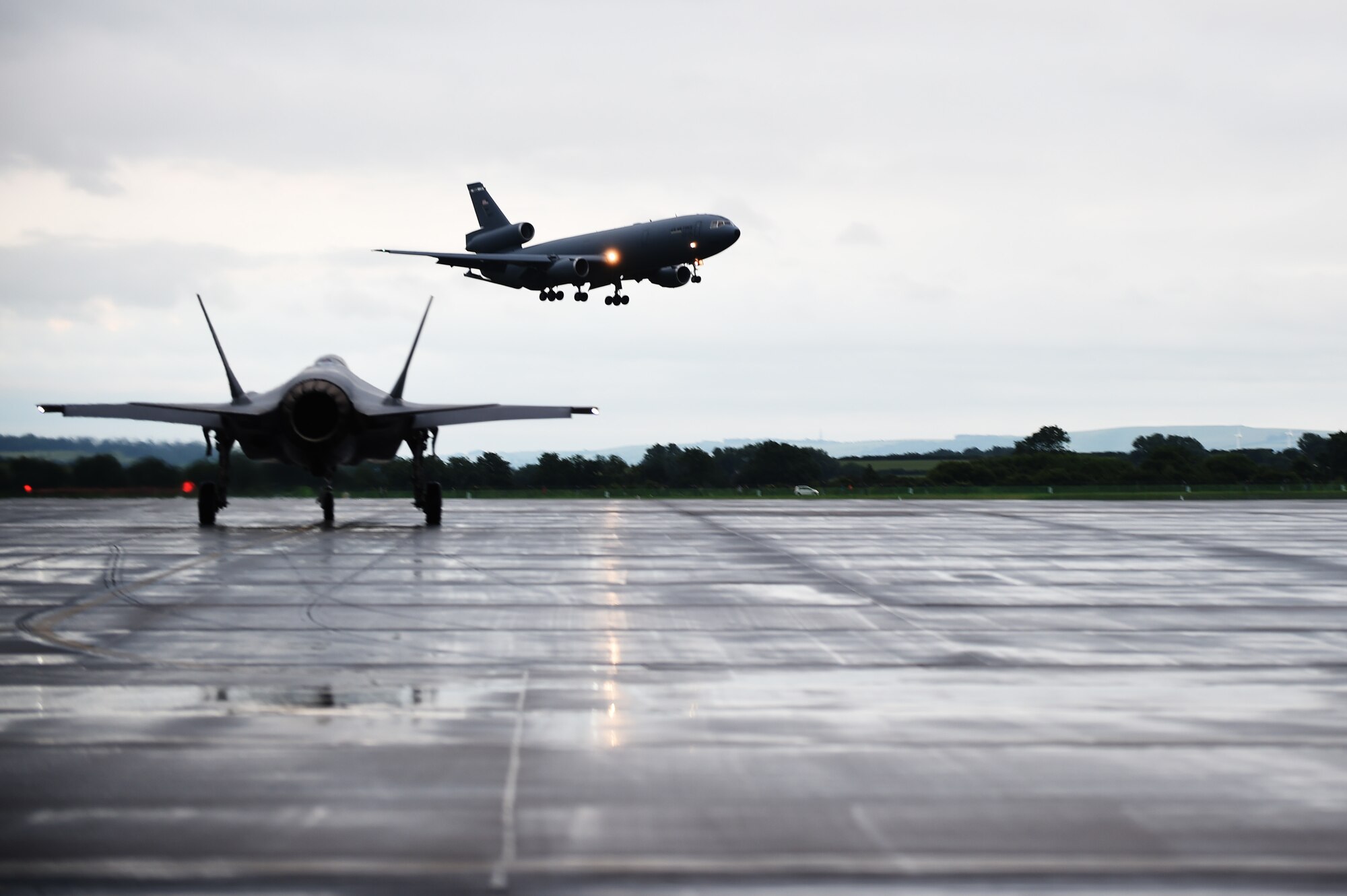 A KC-10 Extender prepares to land, while an F-35A Lightning II taxis down the flightline at RAF Fairford, United Kingdom, June 30, 2016. The KC-10 handled the mid-air refueling of the F-35A's during their transatlantic flight. (U.S. Air Force photo by Tech. Sgt. Jarad A. Denton/Released)