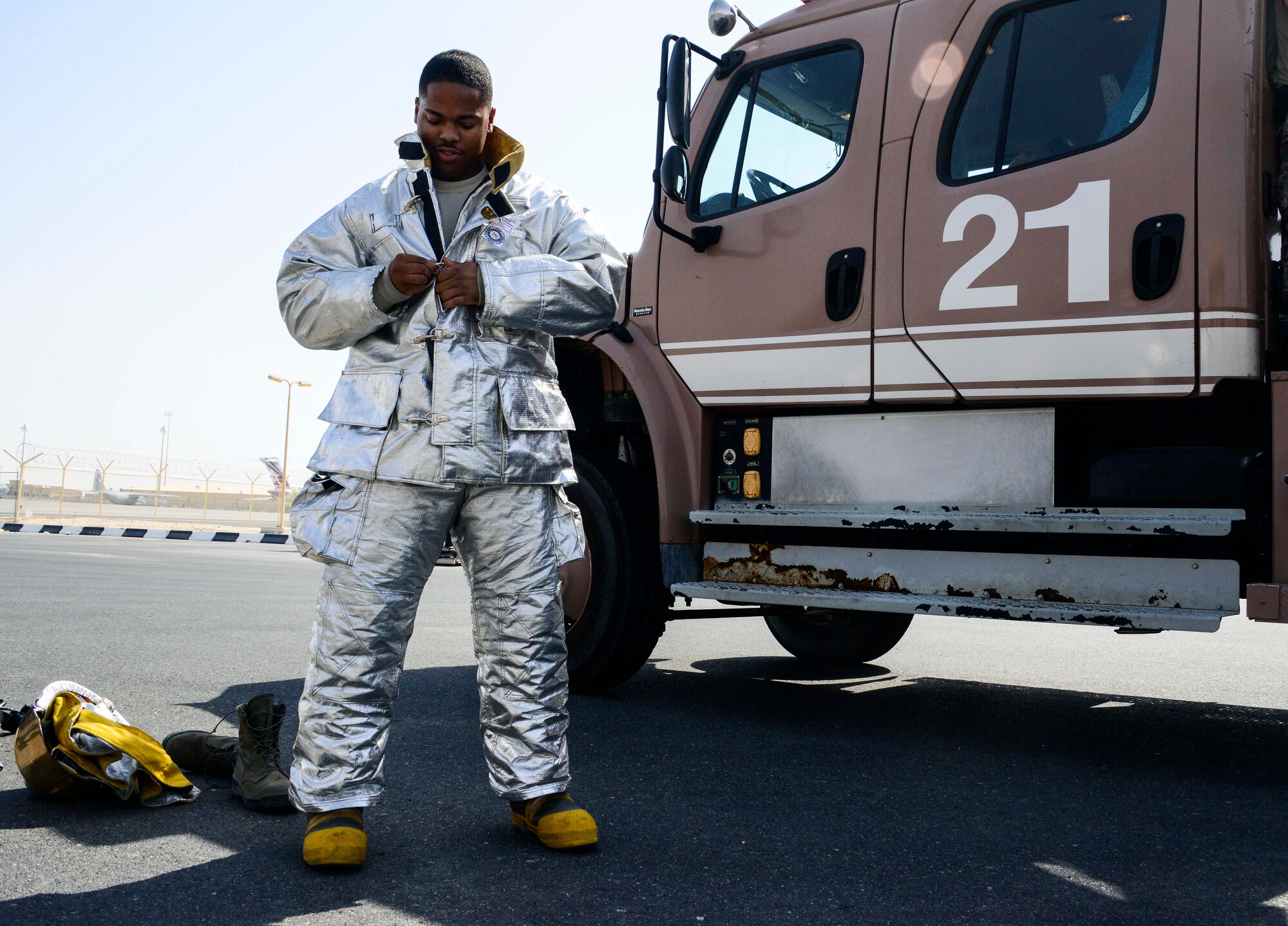Senior Airman Dashawn Gilford, 379th Expeditionary Civil Engineer Squadron firefighter, dons his personal protective equipment prior to stretching a 1 ¾-inch hand line from the side of Engine 21 June 24, 2016, at Al Udeid Air Base, Qatar. The 379th ECES fire department consists of enlisted personnel from Active Duty, Air National Guard and Reserve units. Its structure mirrors most fire departments  to include a fire chief, deputy fire chief, training chief, fire prevention and inspection division, and emergency communications center crew chiefs. (U.S. Air Force photo/Senior Airman Janelle Patiño/Released)