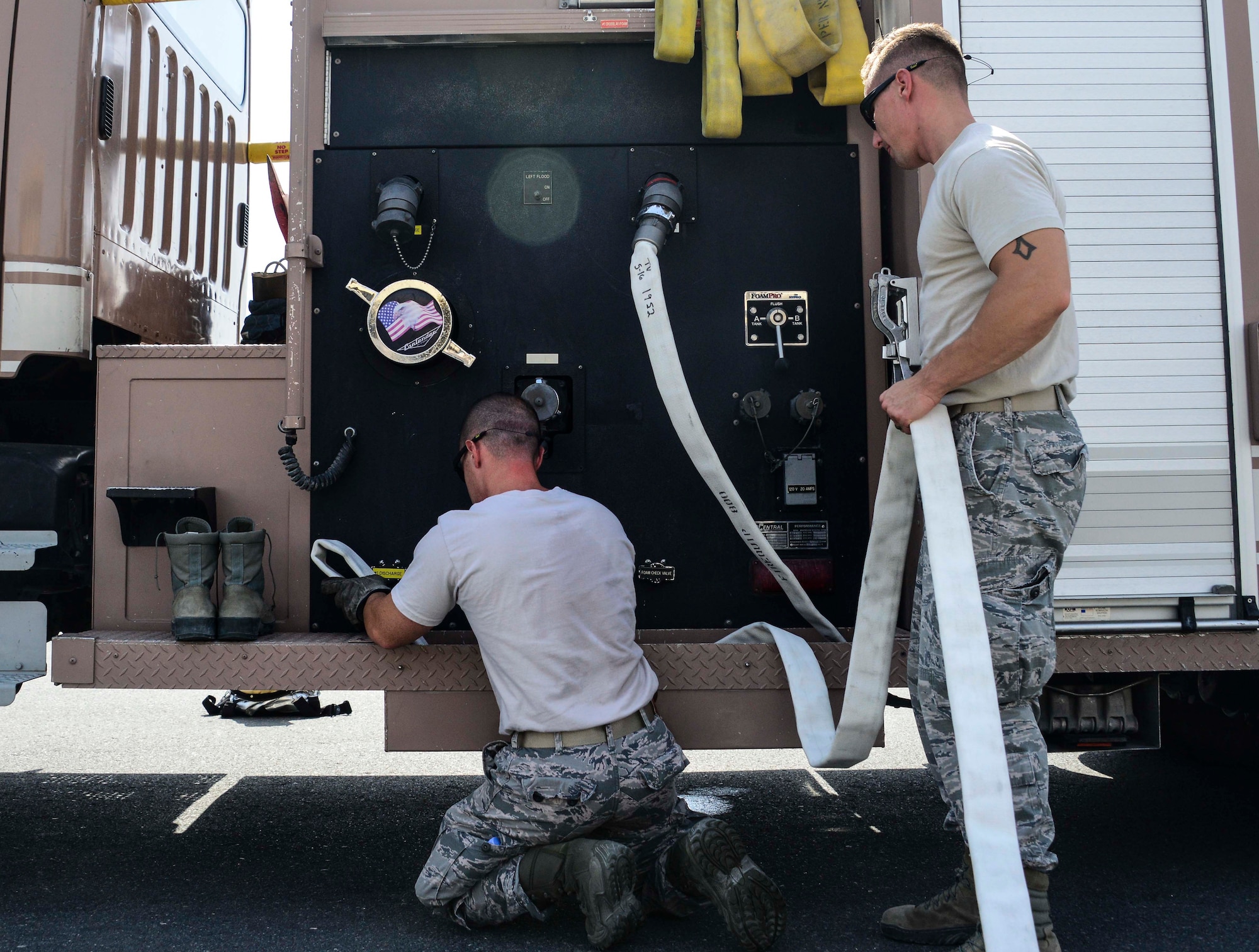 Staff Sgt. Gregory Mazzone, 379th Expeditionary Civil Engineer Squadron firefighter, and Tech. Sgt. Gabriel Boulware, 379th ECES crew chief, repack the 1 ¾-inch hand line from Engine 21 June 24, 2016, at Al Udeid Air Base, Qatar. Repacking a hand line requires certain hose lines loaded in specific ways for different situations. Ensuring the hose is placed back on the Engine 21 correctly is critical to its rapid deployment at the next emergency where it is needed. (U.S. Air Force photo/Senior Airman Janelle Patiño/Released)