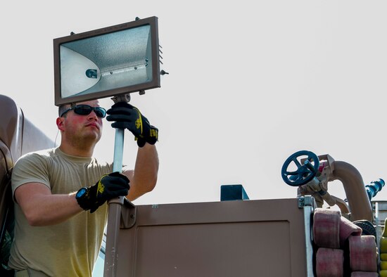 Staff Sgt. Josh Patterson, 379th Expeditionary Civil Engineer Squadron Engine 21 operator, adjusts a scene light prior to operating the fire pump on Engine 21 June 24, 2016, at Al Udeid Air Base, Qatar. The fire department here is the busiest fire department in the Air Force based on call volume.  Despite their operations tempo, the firefighters also assist with fire sprinkler system maintenance and teach fire safety to school children at the American School of Doha. (U.S. Air Force photo/Senior Airman Janelle Patiño/Released)