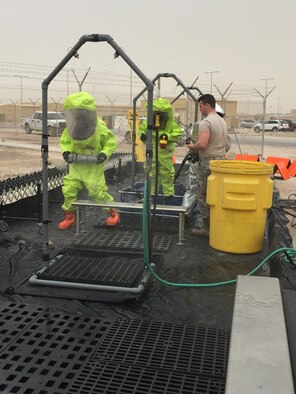 Members of the 379th Expeditionary Civil Engineer Squadron explosive ordnance disposal pass through the technical decontamination corridor to ensure all contaminants are washed off of the responders during a hazardous materials exercise March 16, 2016, at Al Udeid Air Base, Qatar. Members from the fire department, explosive ordnance disposal unit, bioenvironmental engineering, and emergency management participated in the exercise to respond to a simulated reported explosion inside a building and safely inspect the area of any hazardous material. (U.S. Air Force photo/Master Sgt. Jared Mumma/Released)