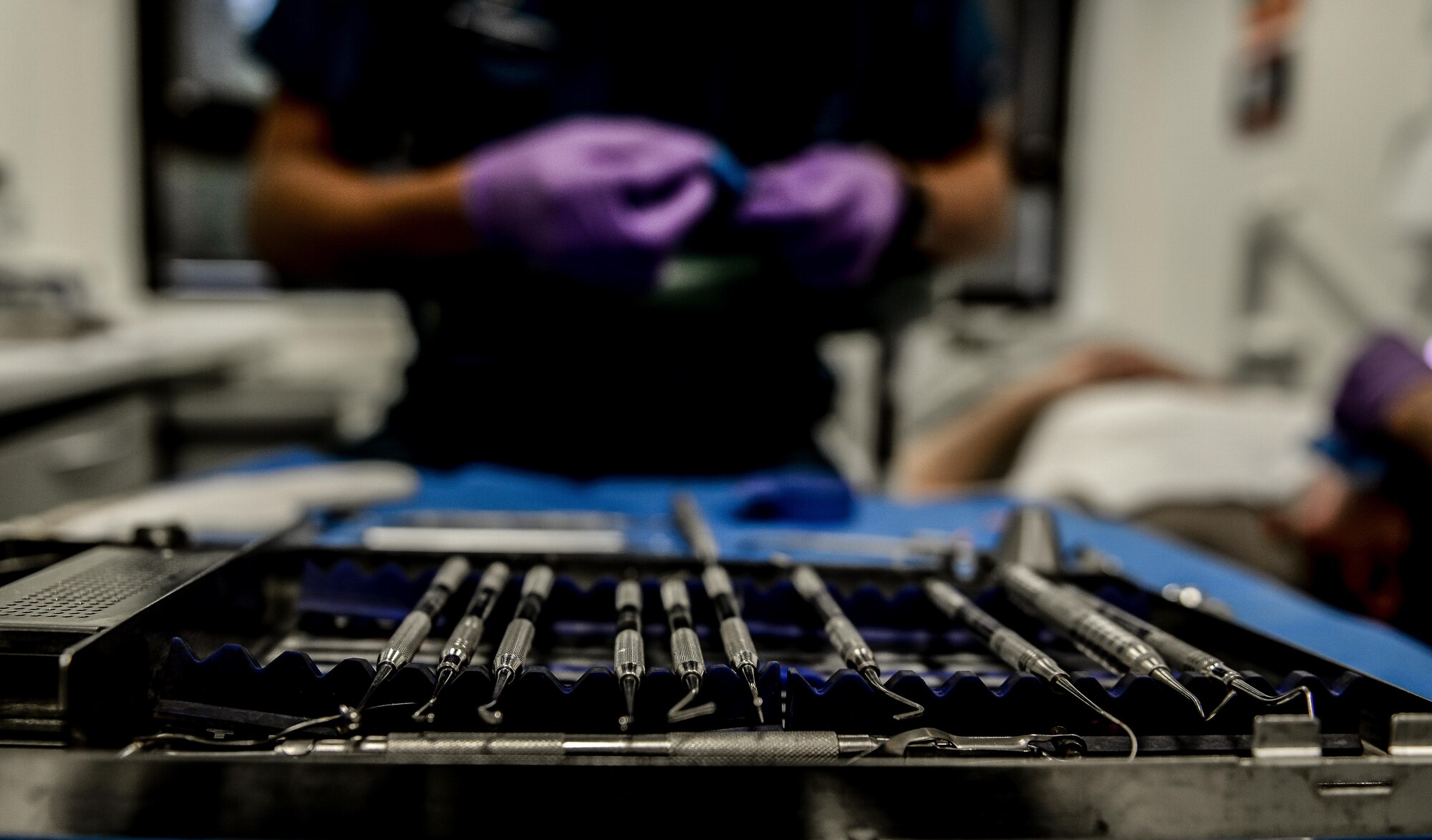 Cleaning tools rest on a table while a dentist operates on a patient at the 86 Dental Squadron at Ramstein Air Base, Germany, July 1, 2016.  The dental team at Ramstein is not only responsible for ensuring the dental health of those within the local area but also of those at 250 geographically separated units. (U.S. Air Force photo/Senior Airman Nicole Keim)