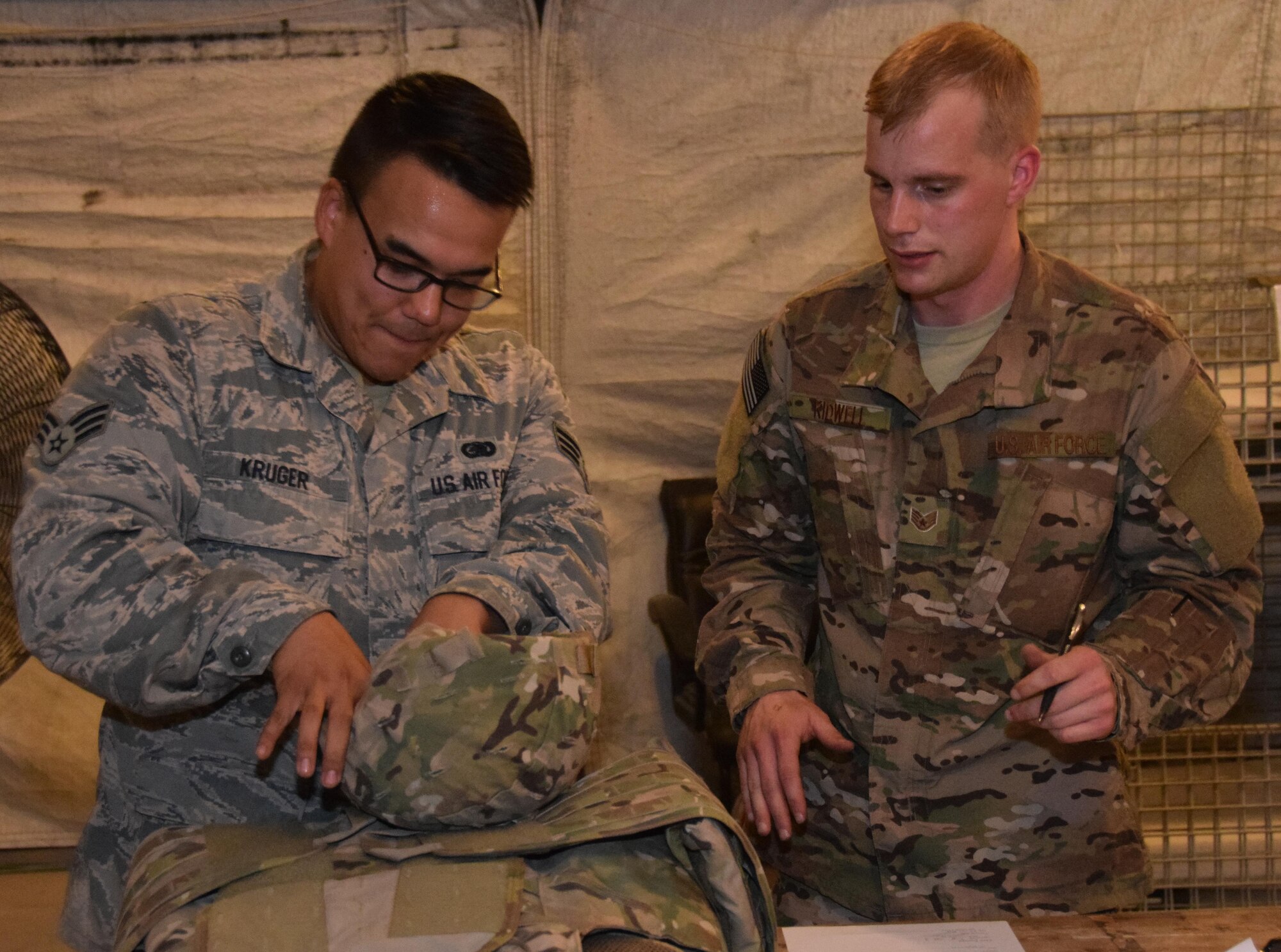 Senior Airman Todd Kruger (left), a 379th Logistics Readiness Squadron customer service journeyman, adjusts a helmet for an Airman as he deploys downrange June 23, 2016 at Al Udeid Air Base, Qatar.  Kruger works in the Expeditionary Theater Distribution Center where attention to detail is key to equipping warfighters Master Sgt. Michelle Guida, ETDC superintendant said.  (U.S. Air Force photo/Technical Sgt. Carlos J. Trevino/Released)